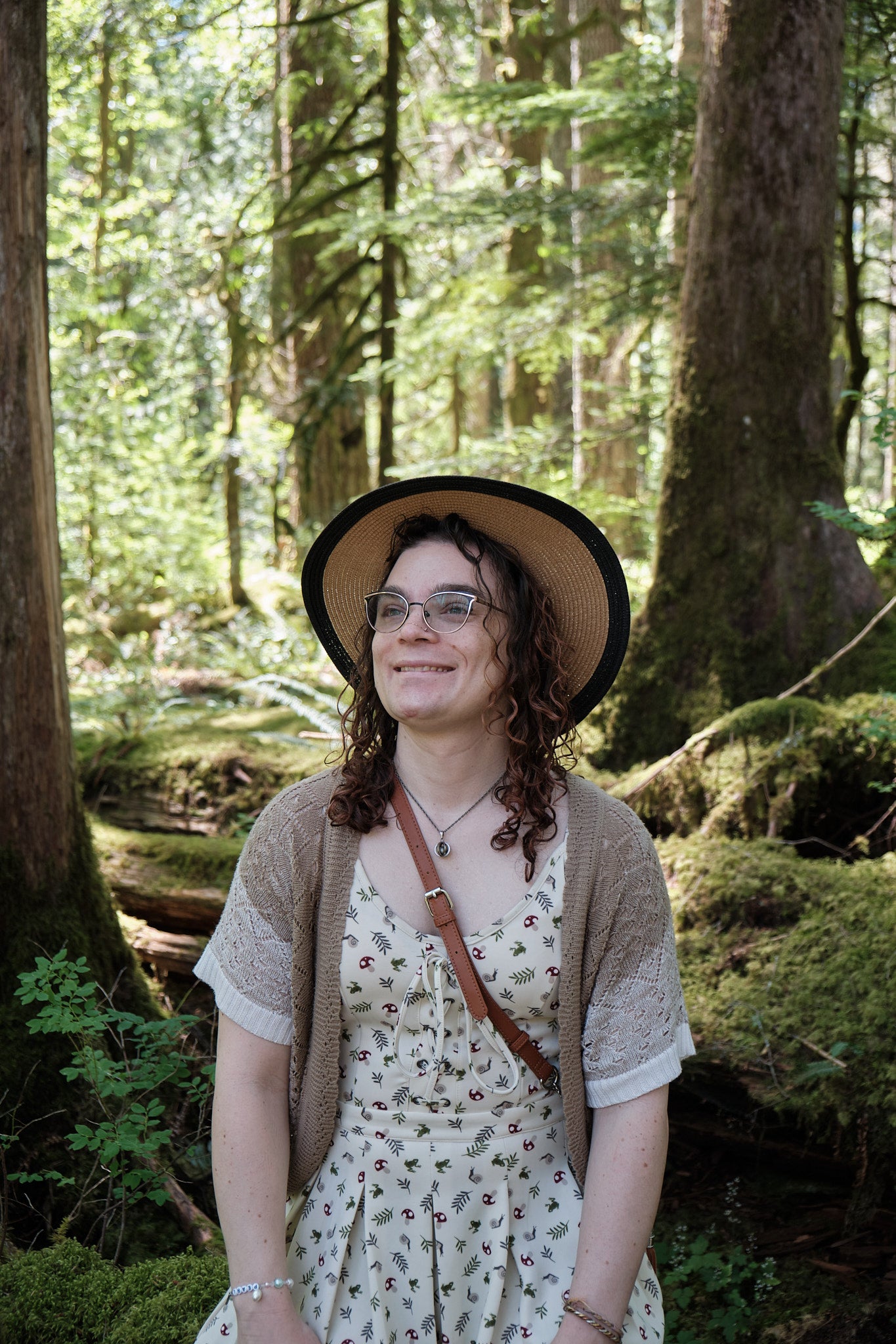 Mel smiling and looking to the side in the woods