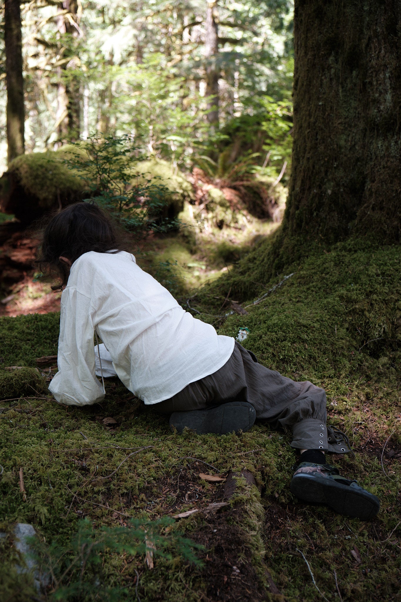 Alex facing away from the camera playing on the mossy forest floor