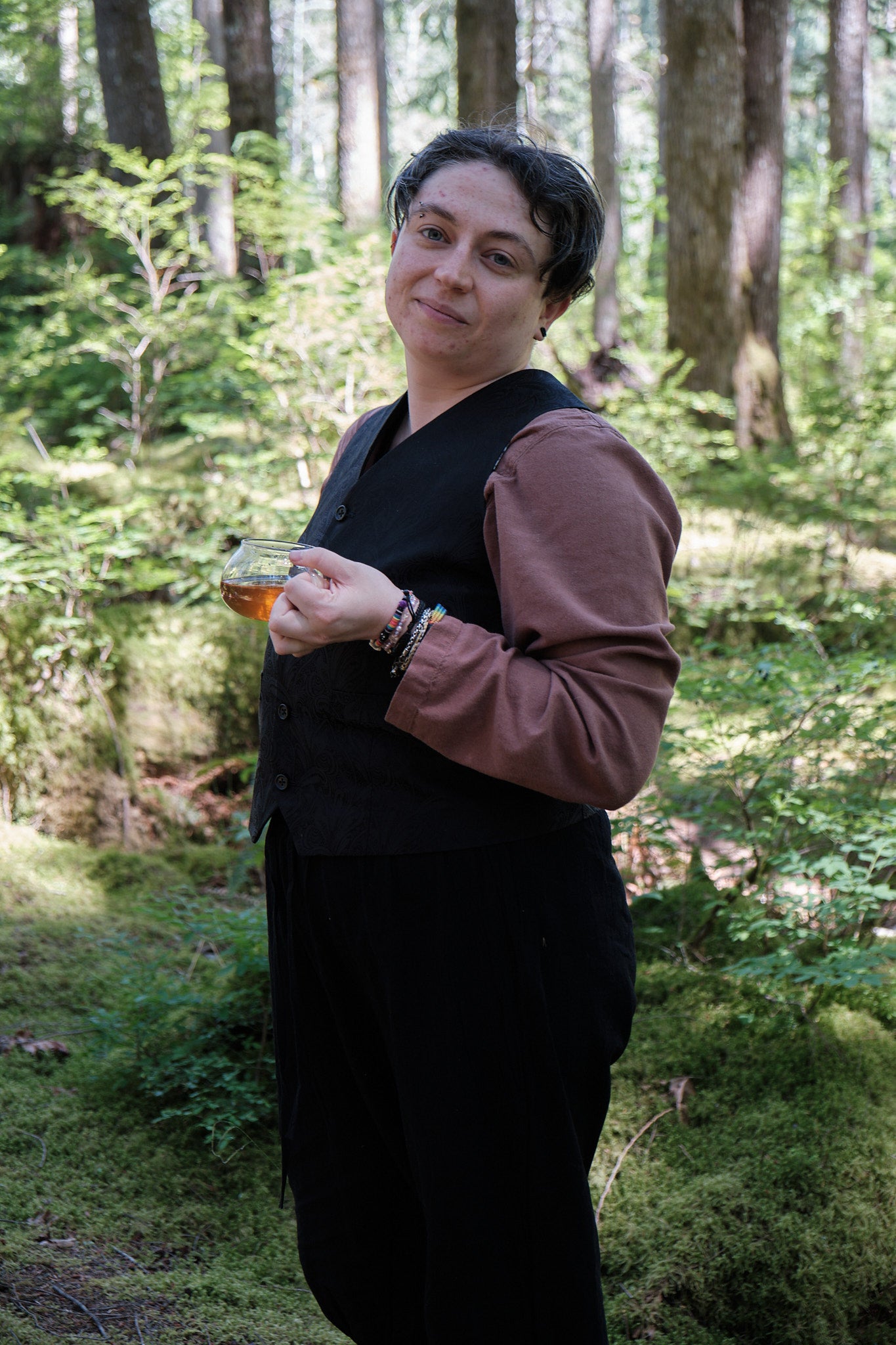 Lee holding a cup of tea in the woods