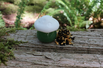 A small mushroom jar on top of a log with tea leaves next to it for one cup.