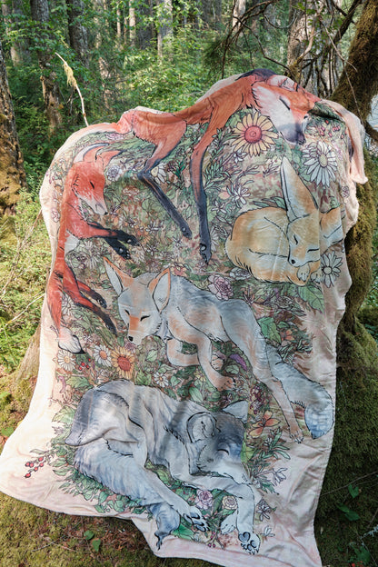 Fuzzy blanket featuring 5 sleeping foxes hanging on mossy stump