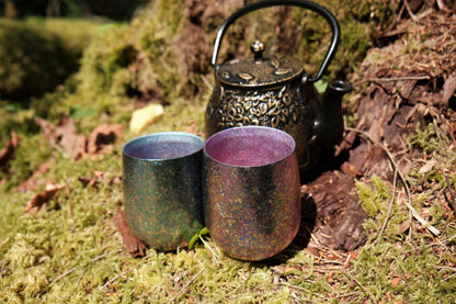 A large and small titanium cup sitting on a bed of moss